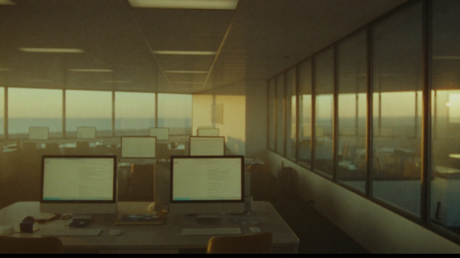 A modern office at dawn with softly glowing screens — the business running itself